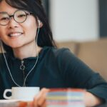 Vrouw met bril en oordopjes bij laptop