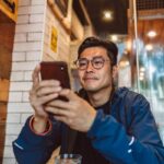Man in café using smartphone, wooden decor background.