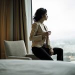 Person sitting by hotel window with city view.