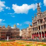 Grote Markt met bloemen, historische gebouwen en mensen.