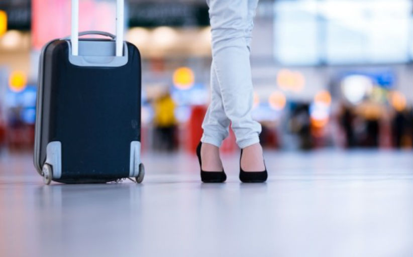 Persoon met koffer wandelt op luchthaven