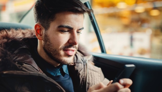 Man leest telefoon in auto.