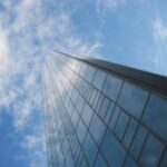 Hoge glazen wolkenkrabber tegen blauwe lucht