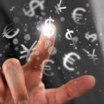 Vinger wijst naar internationale valuta symbolen in de lucht.