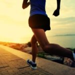 Jogger rent langs zee bij zonsondergang