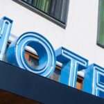 Blauw neon hotelbord met ramen op achtergrond.