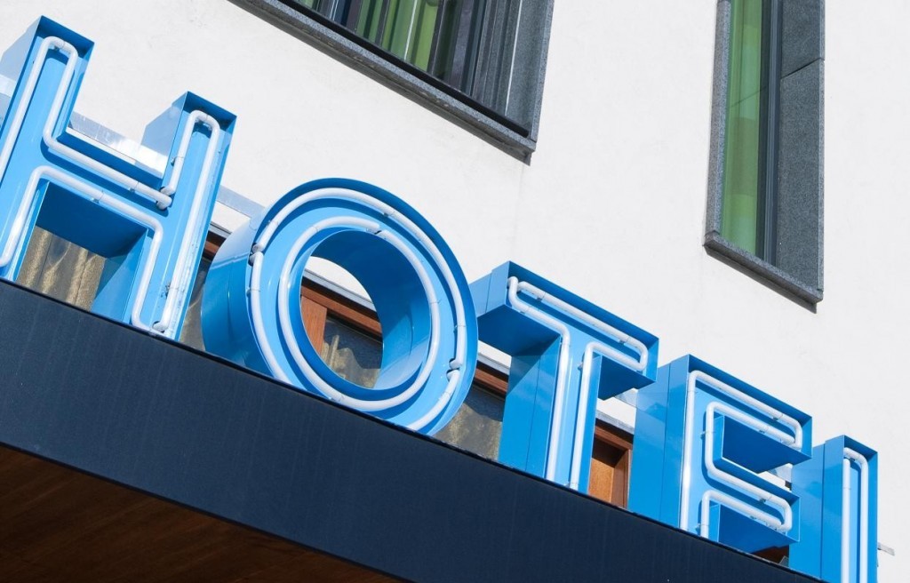Blauw neon hotelbord met ramen op achtergrond.