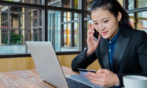 Vrouw telefoneert met laptop en creditcard