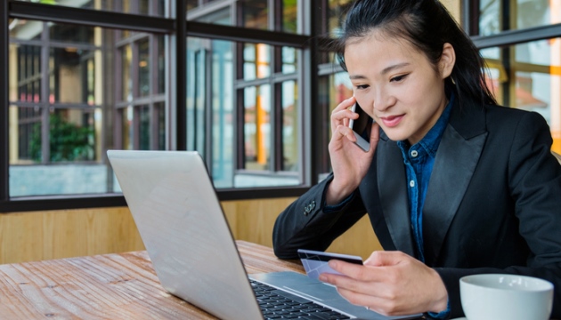 Vrouw telefoneert met laptop en creditcard