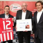 Drie mannen poseren met PSV-shirt en welkomstbord.