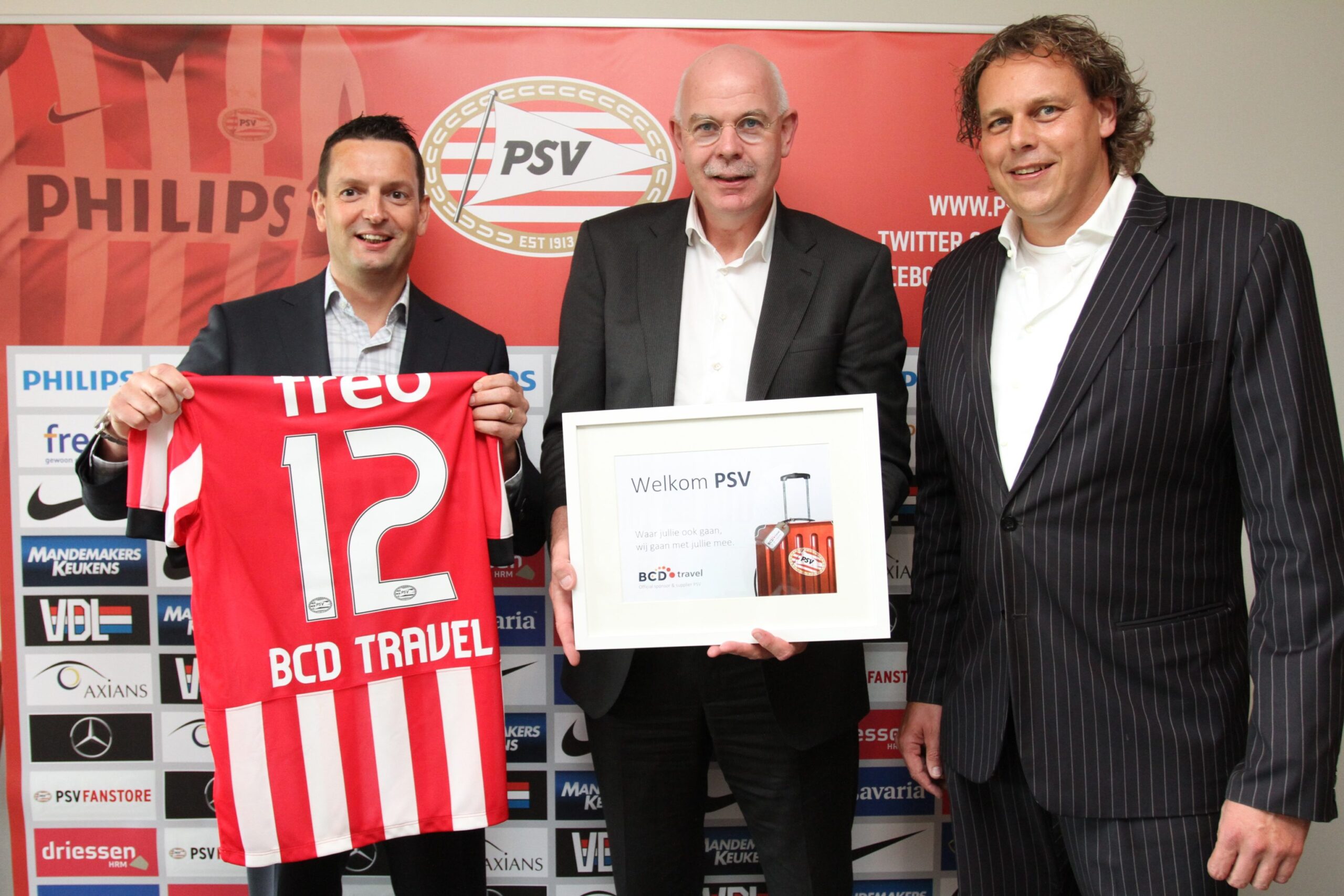 Drie mannen poseren met PSV-shirt en welkomstbord.