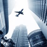 Vliegtuig vliegt boven moderne wolkenkrabbers in de stad.