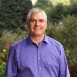 Lachende man in paarse blouse in tuin