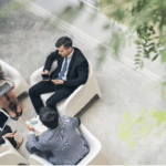 Vier mensen vergaderen met laptops en tablets.