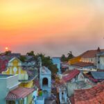 Zonsondergang boven historische stad met torens en daken.