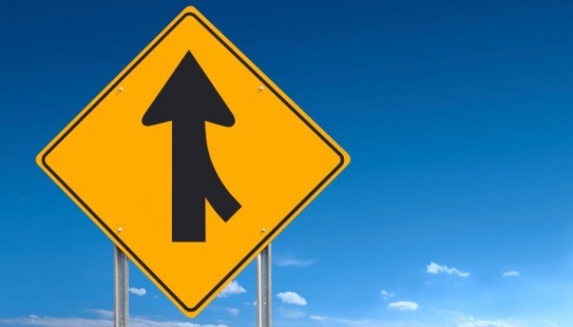 Verkeersbord samenvoegende rijstroken onder blauwe hemel