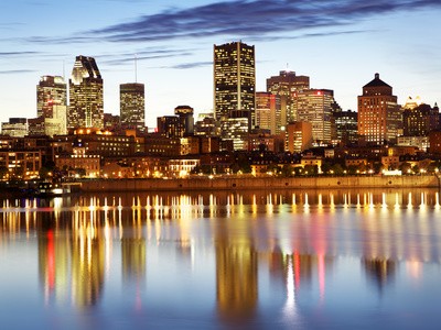 Skyline van Montreal bij zonsondergang, weerspiegeling in water.