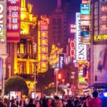 Fel verlichte stadsstraat met veel mensen 's nachts.