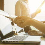 Persoon wijst naar laptop met pen in kantoor.