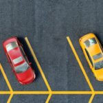 Parkeerplaats met kleurrijke auto's in rijen geparkeerd.