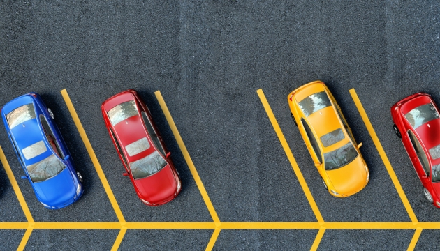 Parkeerplaats met kleurrijke auto's in rijen geparkeerd.