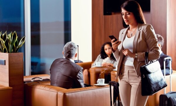 Zakelijke vrouw met smartphone in luchthavenlounge.