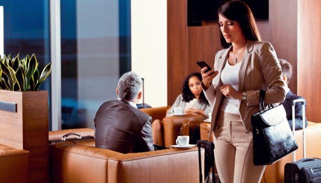 Zakelijke vrouw met smartphone in luchthavenlounge.