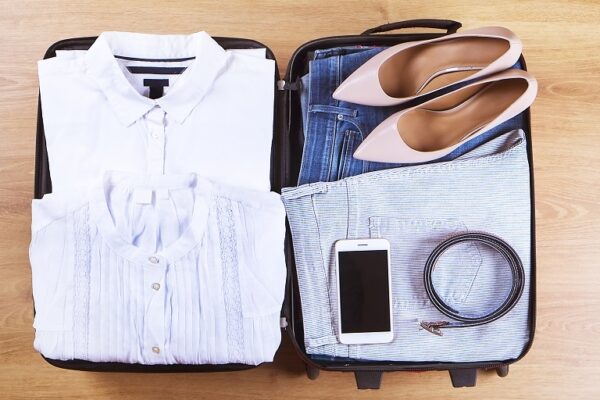 Koffer met kleding, schoenen, telefoon en riem gepakt