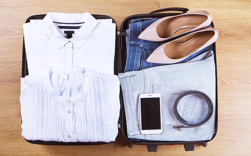 Koffer met kleding, schoenen, telefoon en riem gepakt