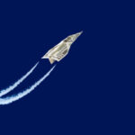 Papieren vliegtuig van geld vliegt omhoog tegen blauwe lucht.