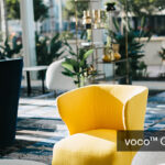 Moderne lounge met gele fauteuil in zonlicht.