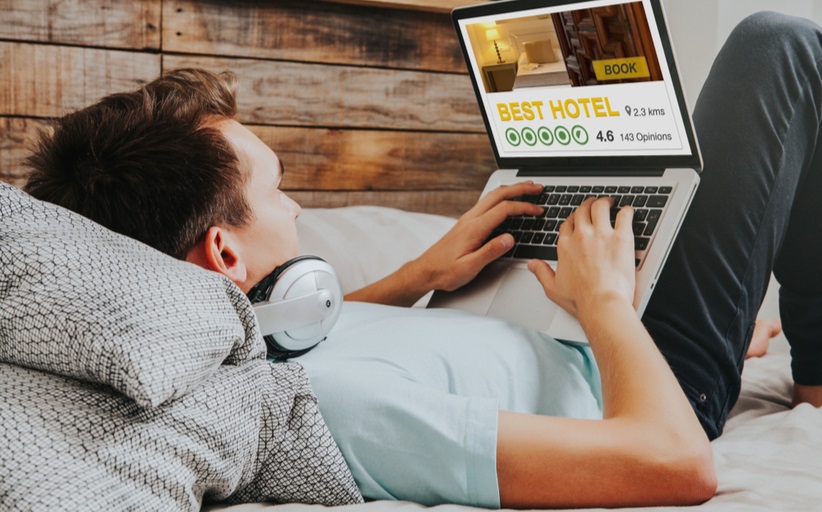 Persoon boekt hotelkamer via laptop op bed