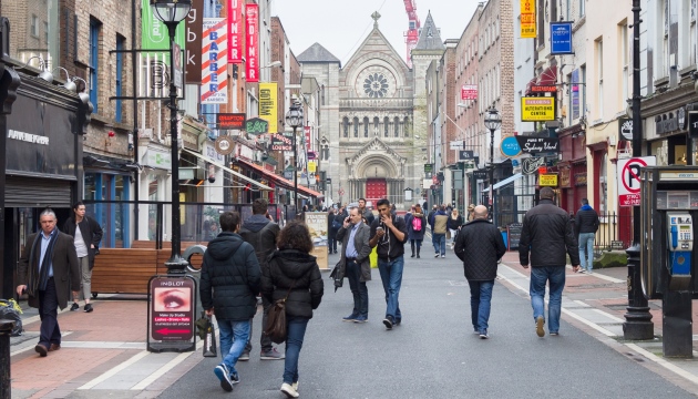 Drukke winkelstraat met kerk op de achtergrond.