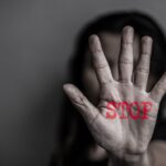 Hand met stopteken in rode letters, focus op hand.