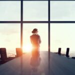 Zakenvrouw kijkt vanuit kantoor bij zonsopgang.