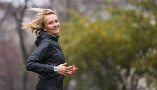 Vrouw jogt buiten in park met groene bomen.