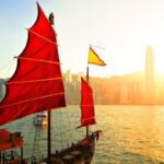 Traditionele Chinese boot met rode zeilen bij zonsondergang.