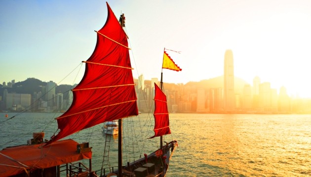 Traditionele Chinese boot met rode zeilen bij zonsondergang.