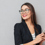 Vrouw glimlachend met smartphone in hand.