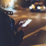 Vrouw gebruikt smartphone op straat 's nachts.