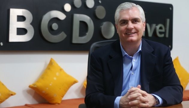 Man voor BCD Travel-logo met gele kussens.