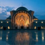 Verlichte moskee bij zonsondergang met reflecties.