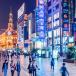 Drukke winkelstraat in de avond met neonlichten.