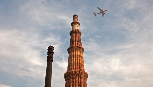 Vliegtuig vliegt boven historische toren in India