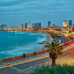 Stad aan zee bij nacht met verlichte gebouwen.