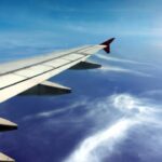 Vleugel van vliegtuig boven wolken en blauwe hemel