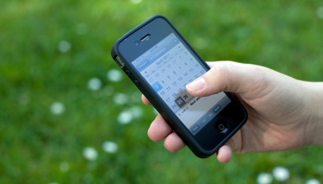 Hand met smartphone en kalender op scherm