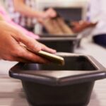 Persoon legt telefoon op bagageband op luchthaven.