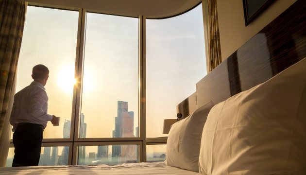 Man kijkt uit raam bij zonsopgang in slaapkamer.