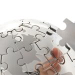 Hand plaatst puzzelstuk in spiegelglobus.